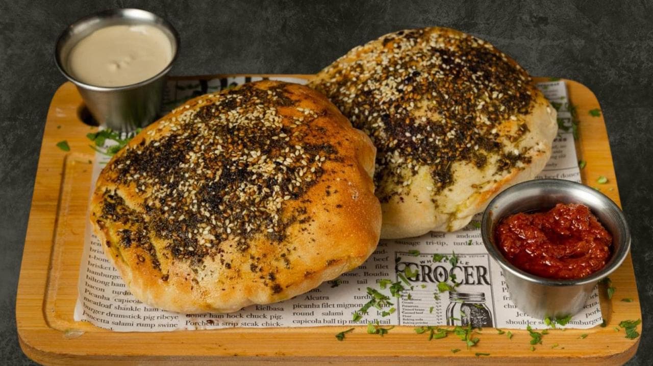 Fresh-baked za'atar flatbread with tahini and harissa